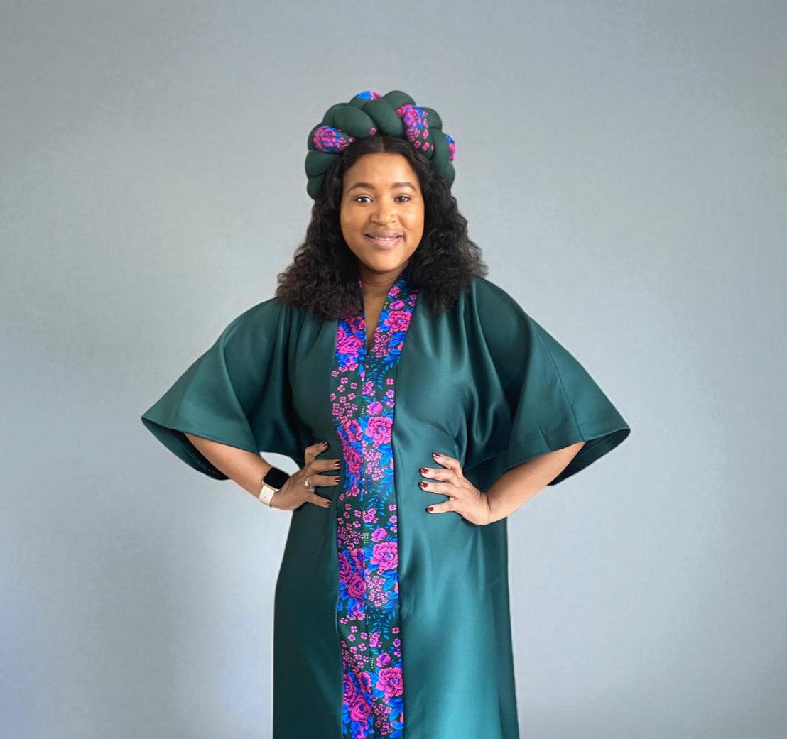 Woman wearing a green traditional outfit with floral patterns on a plain background